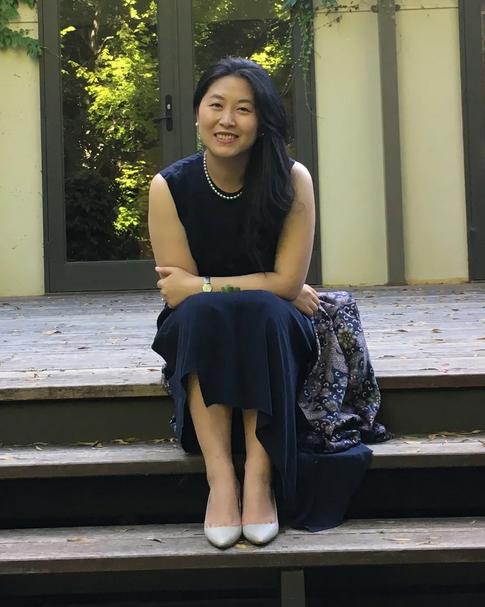 Chun Yin, founder of Base Camp, seated on timber steps outside an ivy-covered building